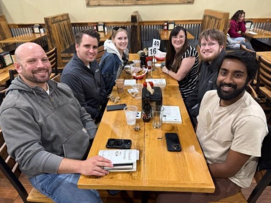 A group of people sitting at a tableAI-generated content may be incorrect.